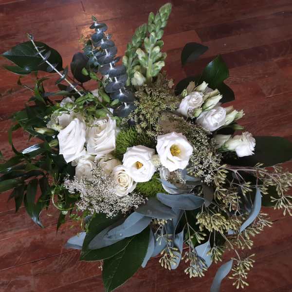 White floral bouquet with eucalyptus and greenery on a wooden floor