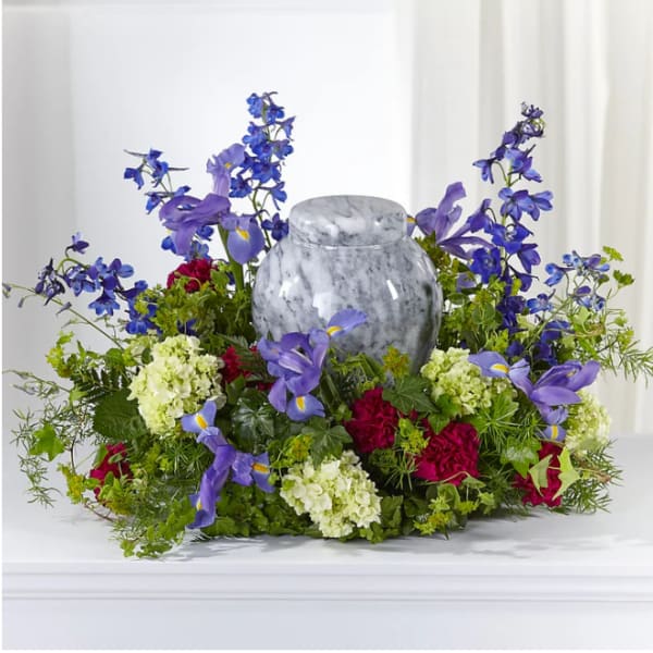 Purple and blue floral arrangement around a gray urn
