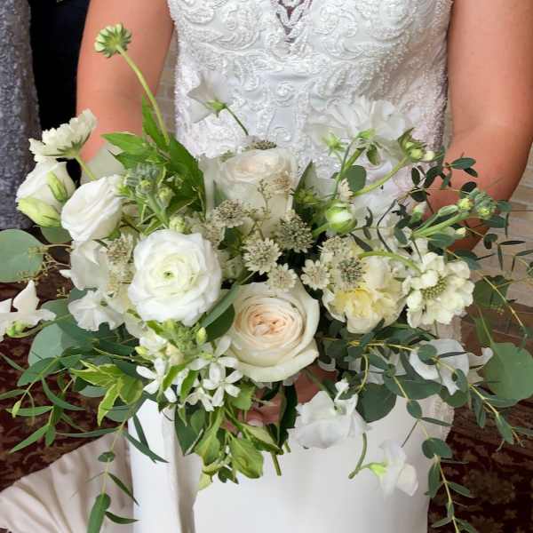Bridal hand-tied bouquet of white and ivory roses with soft greenery accents.