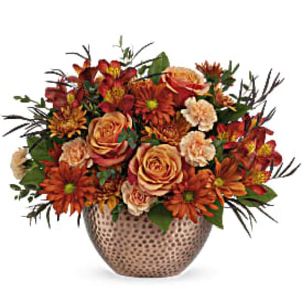 Orange and peach floral arrangement in a patterned vase