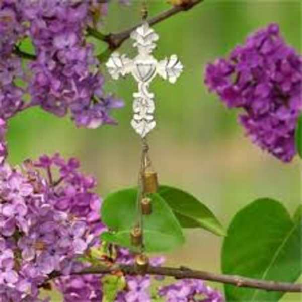 Purple lilac blossoms with a small silver cross ornament hanging among them