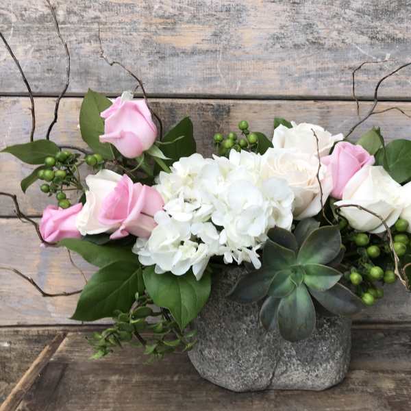Pink and white roses with white hydrangeas in a gray stone vase