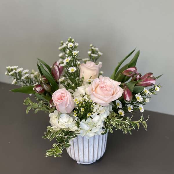 Pink roses and white hydrangeas in a white ribbed vase