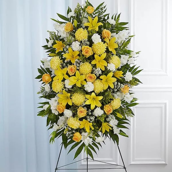Standing floral spray with yellow lilies, roses, and white blooms