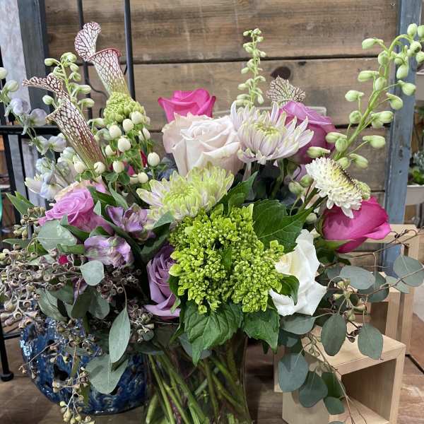 Mixed bouquet of pink, white, and green flowers in a glass vase