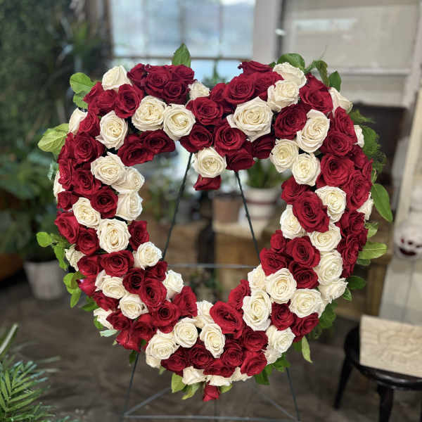 Heart-shaped wreath of red and white roses on a stand