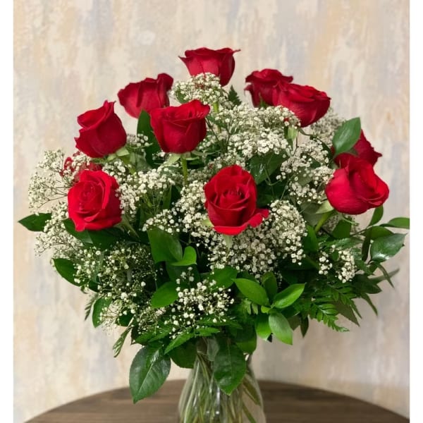 Red roses with baby's breath in a clear glass vase
