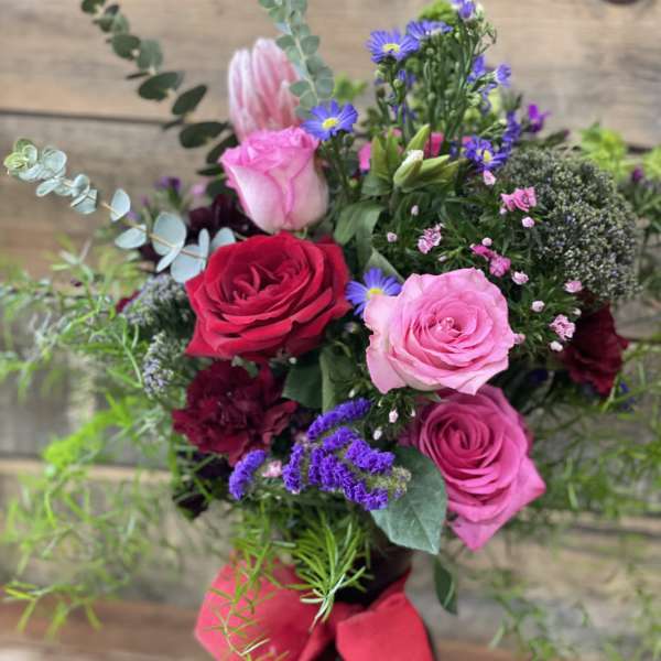 Bouquet of pink and red roses in a dark vase with a red ribbon