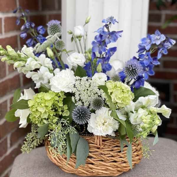 Basket arrangement of blue, white, and green flowers