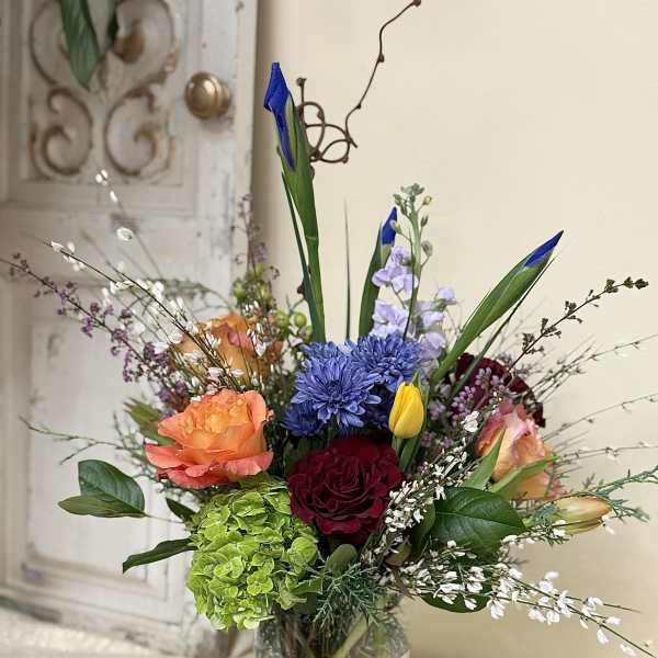 Mixed bouquet in a clear glass vase with roses, chrysanthemums, and tulips