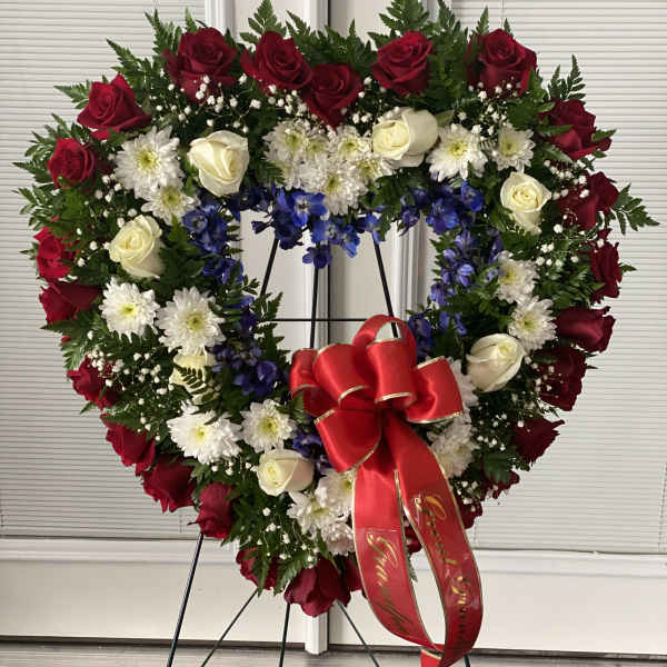 Heart-shaped floral wreath with red and white roses on a stand