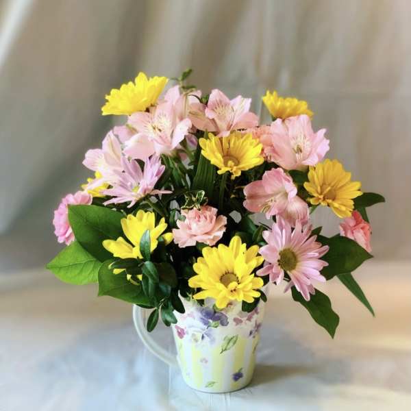 Pink and yellow flowers arranged in a floral mug