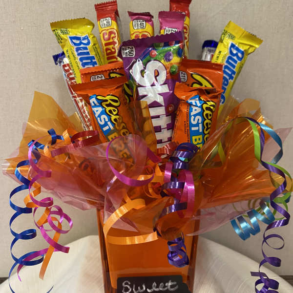 Candy bouquet in an orange vase with curled ribbons