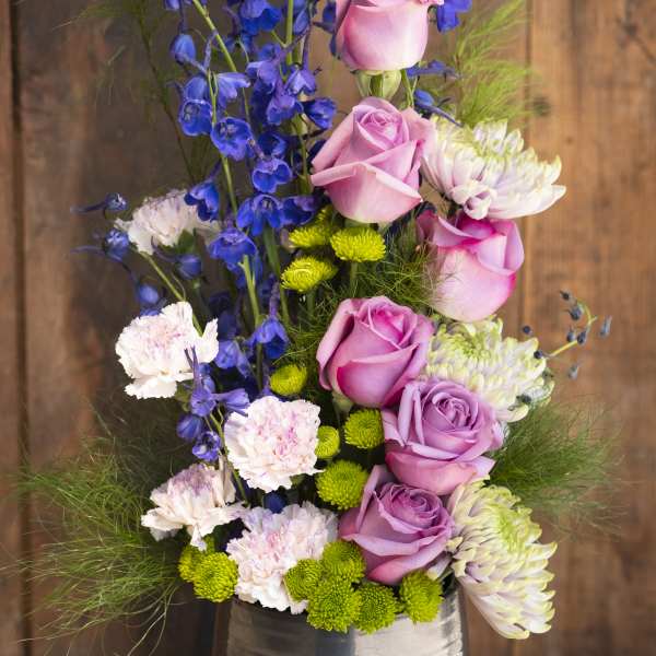 Pink roses and blue delphinium in a silver vase