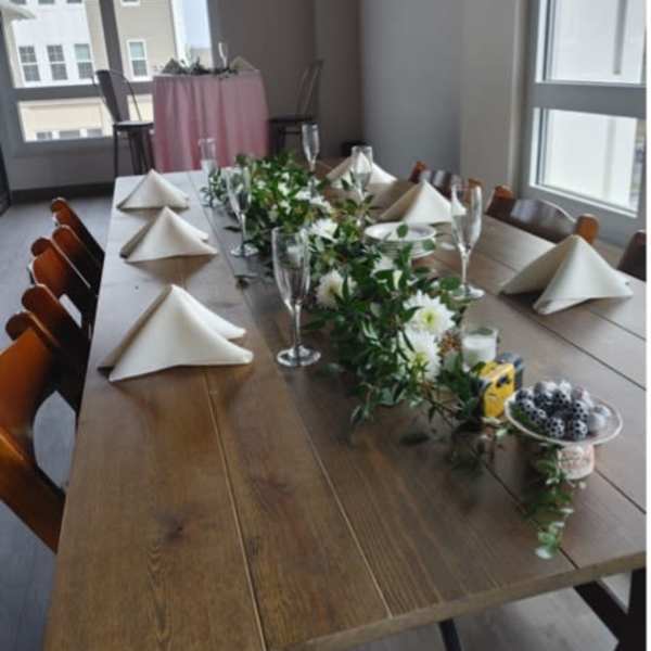 Long table with white floral garland and folded napkins set for an event