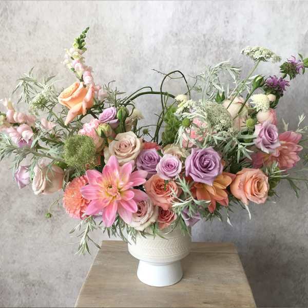 Pastel bouquet of roses, dahlias, and snapdragons in a white vase