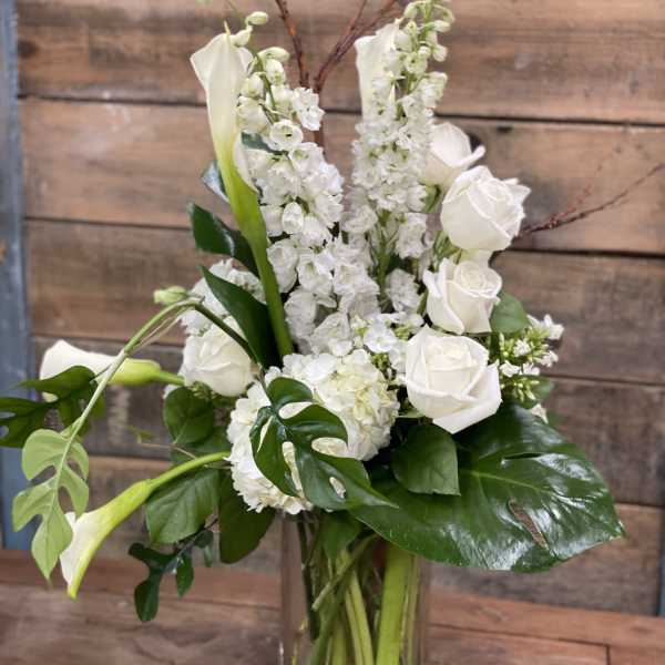 White roses and calla lilies in a clear glass vase