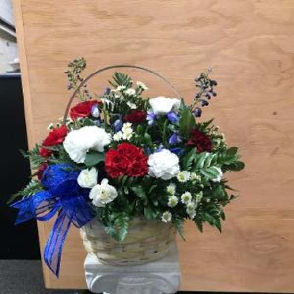 Basket arrangement of red, white, and blue carnations on a pedestal