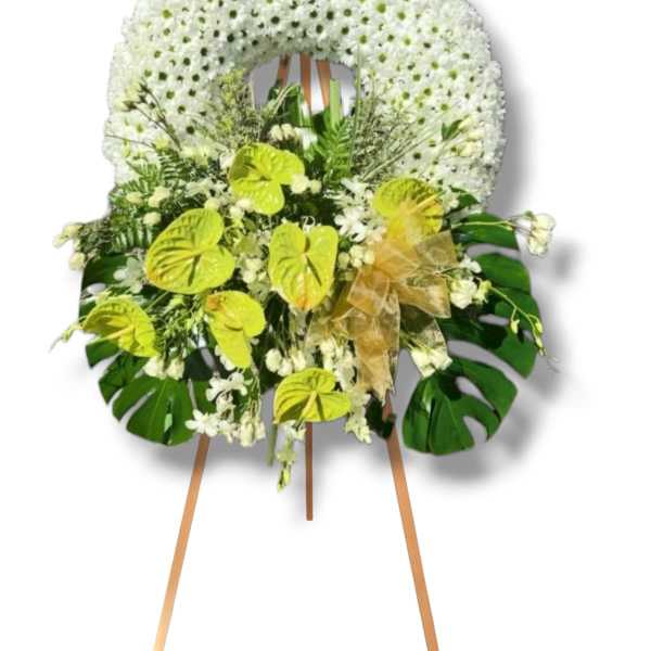 White floral standing wreath on an easel with green accents