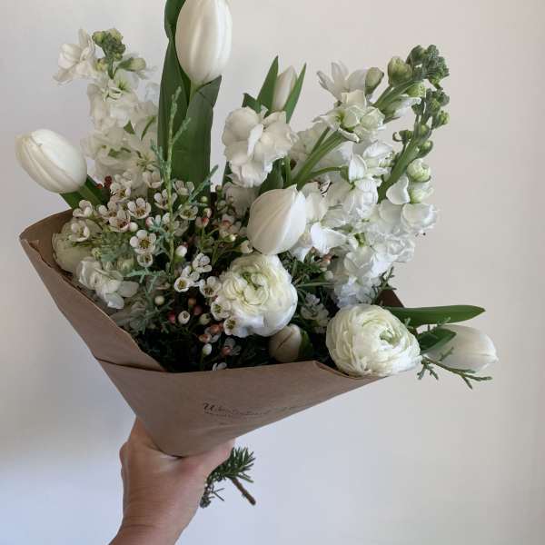 White tulips and ranunculus in brown paper wrapping