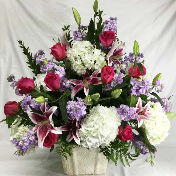 Large bouquet of pink roses, white hydrangeas, and purple lilies in a white vase