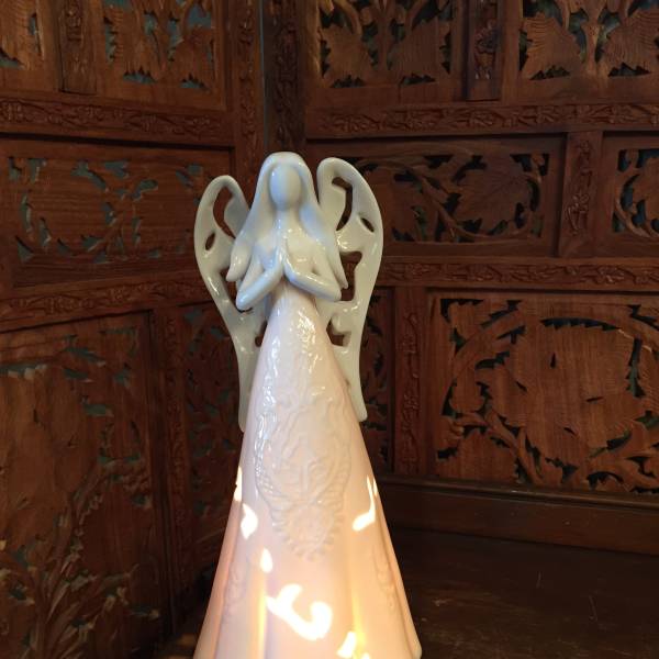 Ceramic angel figurine beside a small square candle holder