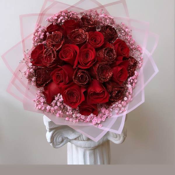 Bouquet of red roses with pink baby's breath and translucent pink wrap