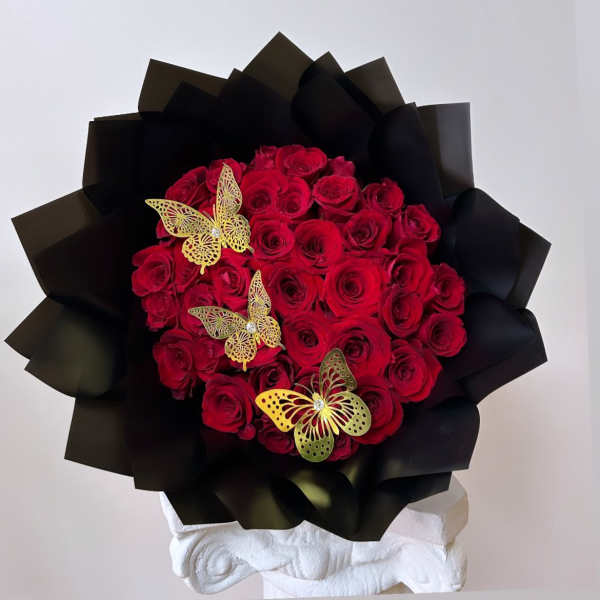 Bouquet of red roses wrapped in black paper with gold butterfly accents