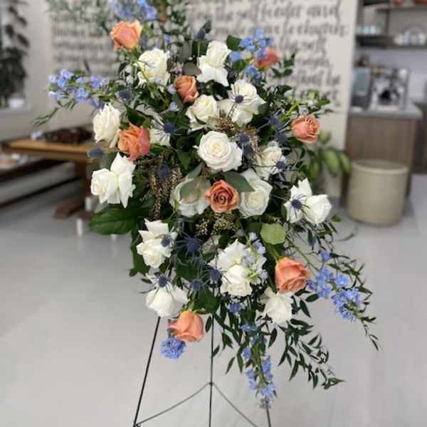 Standing floral spray with white and peach roses and blue accents