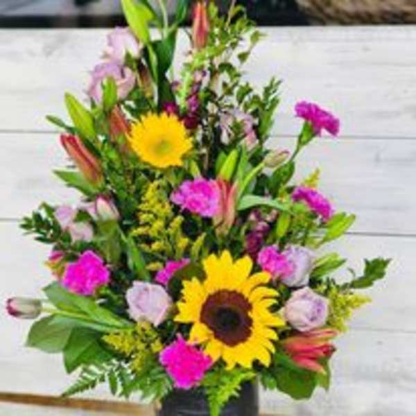 Tall mixed bouquet with sunflowers, pink blooms, and lilies in a vase