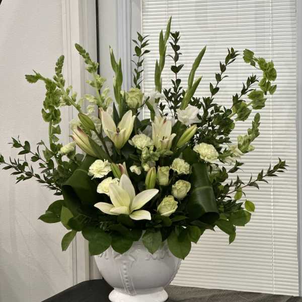 White lilies and pale carnations in a white urn vase