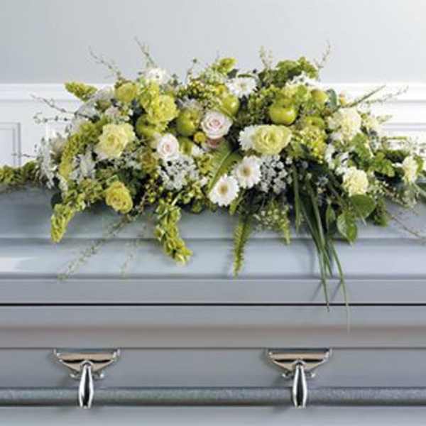 White and pale green floral casket spray on a gray casket