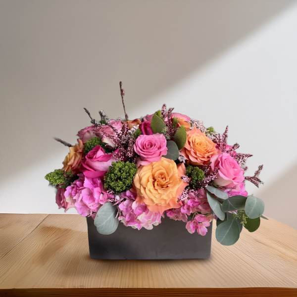 Pink and peach roses arranged in a black rectangular box