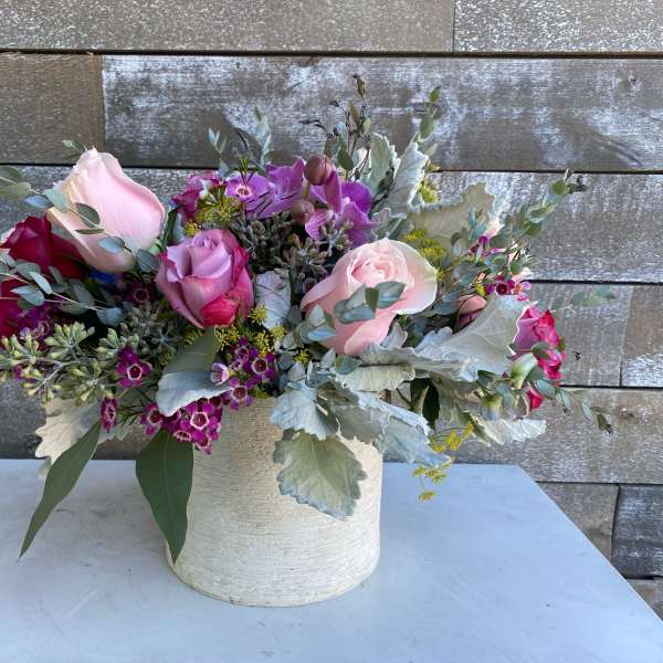 Pink and purple roses arranged in a white vase