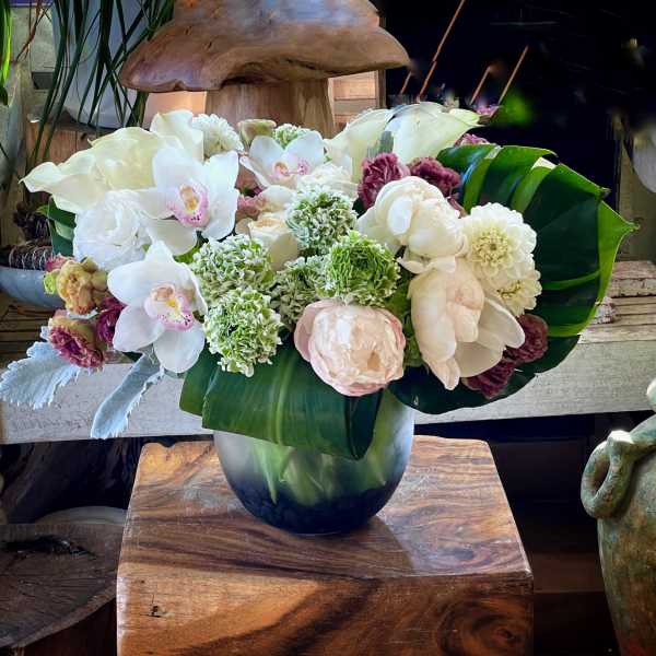 White orchids and pale blooms arranged in a glass vase