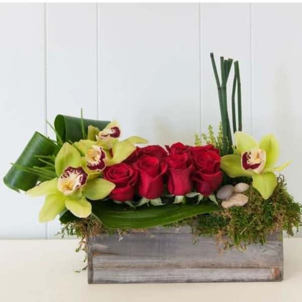 Red roses and green orchids in a wooden box arrangement