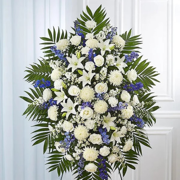Large white and blue funeral spray on a stand
