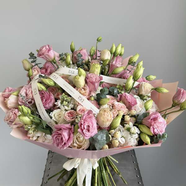 Large bouquet of pink and cream roses with white blooms wrapped in pink paper