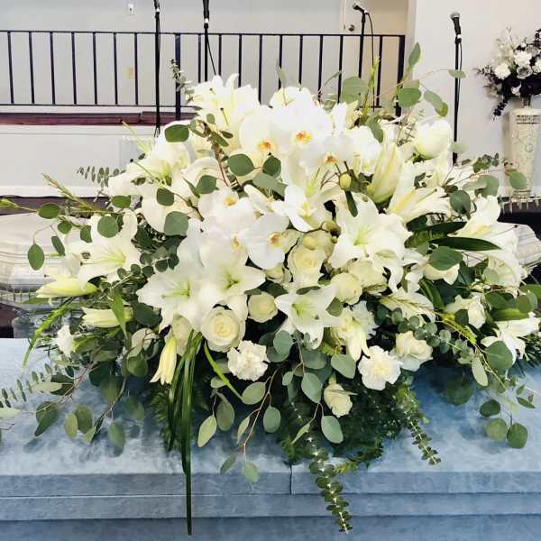 Large white floral casket spray with lilies and orchids