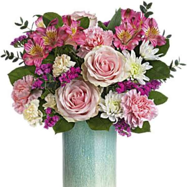 Pink roses and mixed blooms in a tall blue vase