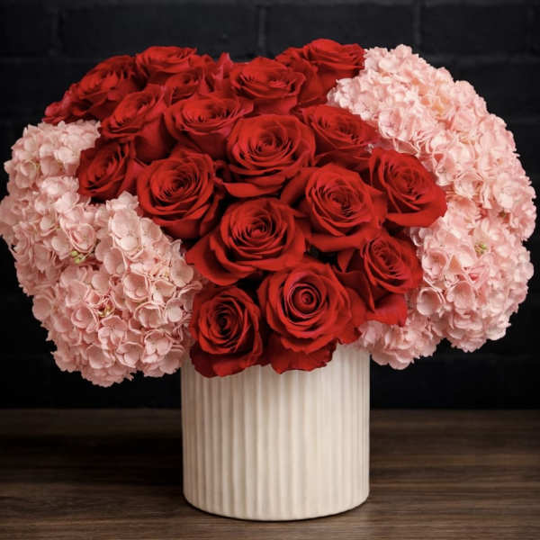 Red roses and pale pink hydrangeas in a white vase