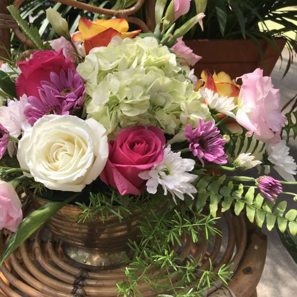 Mixed bouquet of roses, hydrangea, and daisies in a copper vase