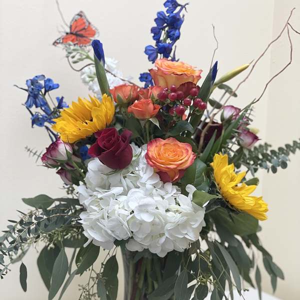 Colorful bouquet of roses, hydrangea, and sunflowers in a glass vase