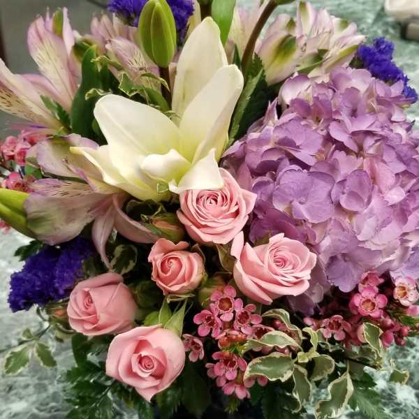 Mixed bouquet with pink roses, white lilies, and purple hydrangea in a vase