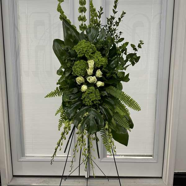 Tall green floral standing spray on an easel with white roses