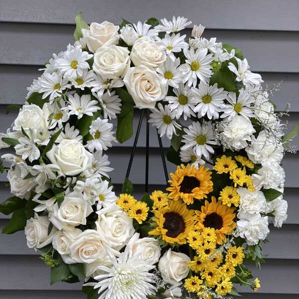 Heart-shaped floral wreath with white roses, daisies, and yellow sunflowers