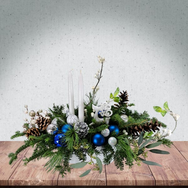 Holiday centerpiece with white candles, pinecones, and blue ornaments