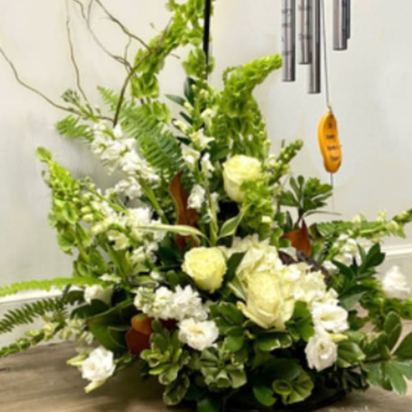 White floral arrangement with a hanging wind chime above it