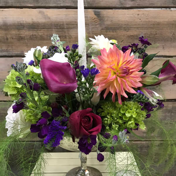 Colorful floral centerpiece with a white taper candle in a silver holder