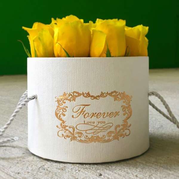 Yellow roses in a white round gift box with gold lettering